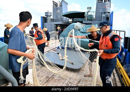 (240621) -- SANSHA, 21. Juni 2024 (Xinhua) -- Gesetzesvollstrecker der chinesischen Küstenwache helfen chinesischen Fischern, die entnommenen Fischernetze auf einem Fischerboot im chinesischen Ren'ai Jiao und dem umliegenden Territorialmeer zu arrangieren, 11. Juni 2024. Vor kurzem beschädigten Mitarbeiter des illegal geerdeten philippinischen Marinetransportschiffs im chinesischen Ren'ai Jiao und im umliegenden Territorialmeer wiederholt die Netze der chinesischen Fischer und setzten die illegal beschafften Fischernetze in die nahe gelegenen Gewässer ihres Schiffes ein, um die Strafverfolgung der chinesischen Küstenwache (CCG) zu behindern. Die Ermittler der CCG haben diese i wiedergefunden Stockfoto