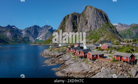 Ein malerischer Blick auf die roten Hütten an den felsigen Ufern eines Fjords in Norwegen. Umgeben von majestätischen Bergen, Hamnoy Fischerdorf auf den Lofoten Inseln, Norwegen mit roten Rrorbu-Häusern Stockfoto