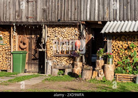 Brennholzhaufen dekoriert mit Blumen und Gartenobjekten, Brennholzvorrat für den Winter, Gartendekoration, Sommerzeit Stockfoto