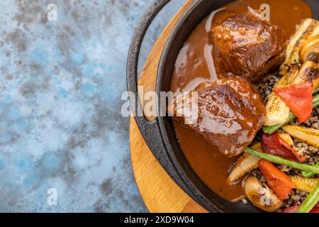 Aus nächster Nähe sehen Sie leckeres Gulasch - gegrilltes und geröstetes Rindfleisch mit Maiskolben, Spargel, Quinoa auf heißer Pfanne. Essen im Restaurant zum Mittagessen. Essen Foto Backgrou Stockfoto