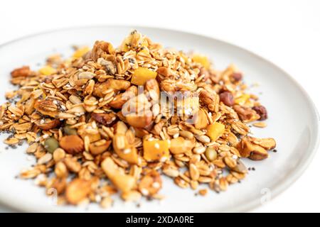 Eine Schüssel Müsli mit Nüssen und Samen auf einem weißen Teller. Das Müsli ist eine Mischung aus verschiedenen Getreidearten und Nüssen, und es sieht aus wie ein gesunder Snack Stockfoto