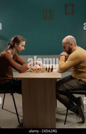 Männliches Paar im Wohnzimmer, Spaß beim Schach spielen und gemeinsame Freizeit zu Hause genießen Stockfoto