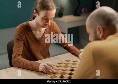 Freunde, die zu Hause Ein Spiel der Checkers genießen. Freundliches Checkers Match, Freizeit Im Komfortablen Wohnzimmer Stockfoto
