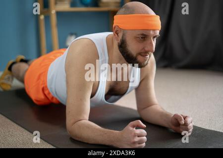 Ein Mann mittleren Alters macht eine Übungsplanke. Gesundes Lifestyle-Konzept. Sportler gehen zu Hause zum Sport. Stockfoto
