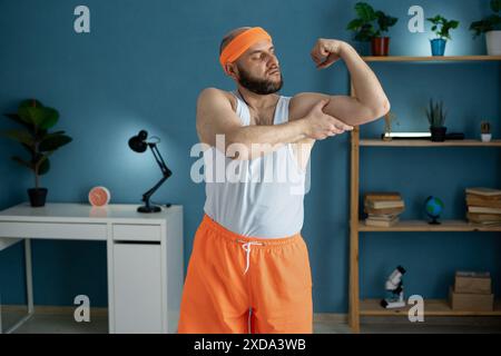 Porträt eines glücklichen, Reifen Mannes, der im Top-Tank einen Bizeps zeigt Stockfoto