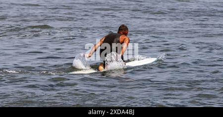 Rückansicht eines Mannes, der auf seinem Surfbrett kniet und zu den Wellen am Gilgo Beach auf Long Island paddelt. Stockfoto