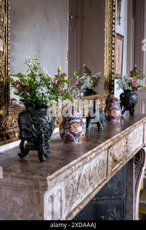 Schnittblumen und orientalische Urnen am Marmorkamin in in Saulieu, Burgund, Frankreich. Das renovierte Hotel stammt aus dem Jahr 1770. Stockfoto