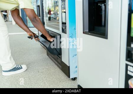 Ein Mann benutzt einen Automaten, um einen Drink zu bekommen. Der Automat verfügt über einen Wasserspender und einen Spender für Soda Stockfoto