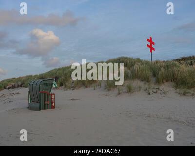 Einsame Liege neben Dünen mit rotem Kreuz im Hintergrund, Juist, Nordsee, Deutschland Stockfoto