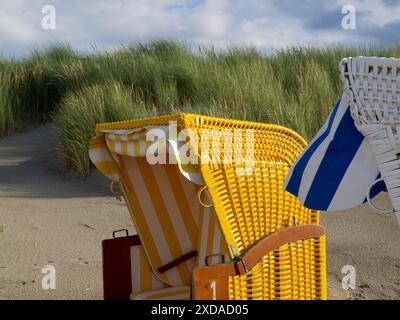 Nahaufnahme einer gelben und einer weißen Liege nebeneinander an einem Sandstrand vor grasbewachsenen Dünen, Juist, ostfriesland, deutschland Stockfoto