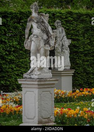 Steinskulpturen umgeben von bunten Blumen in einem gepflegten Garten, trier, deutschland Stockfoto