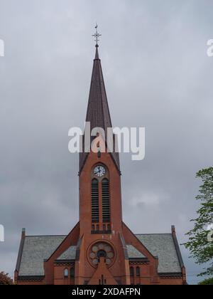 Kirchturm aus rotem Backstein mit Uhr und architektonischen Details unter bewölktem Himmel, haugesund, norwegen Stockfoto