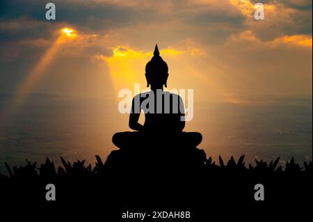 Buddha Statue Silhouette Buddha sitzt auf Lotusblume auf orangem Hintergrund Stockfoto