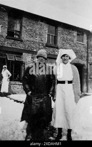 Eine Krankenschwester in Uniform und ein Mann im langen Mantel vor einem Krankenhausgebäude. Mode und Kultur. Aus einer Sammlung von Schnappschussfotos einer Gruppe von Frauen, 1928. Es gab nur wenige Anmerkungen auf den Fotos, aber die Frauen schienen als Gruppe zu reisen und hatten eindeutig eine Vorliebe für die englische Grafschaft Kent. Einige der Fotos deuten darauf hin, dass sie Feministinnen ihrer Zeit waren, und obwohl sie weitgehend unbekannt sind, habe ich sie aufgenommen, da sie einige der Mode der Zeit repräsentieren. Stockfoto