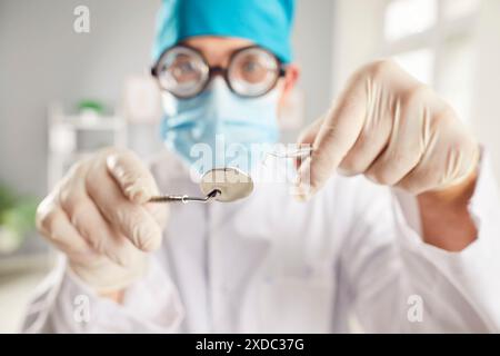 Hände eines lustigen Arztes, der Zahnwerkzeuge in medizinischer Uniform in der Zahnarztpraxis hält. Stockfoto
