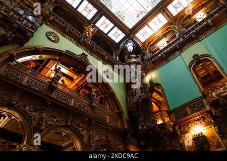 Sinaia, Rumänien - 26. August 2022: Wendeltreppe mit Holzschnitzereien und Holzdekoration im Ehrensaal im Schloss Peles. Das reichhaltige Interieur Stockfoto