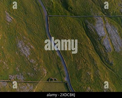 Ein Top-Down-Bild, das eine Serpentinenstraße durch eine zerklüftete, natürliche Landschaft mit strukturiertem Gelände einfängt Stockfoto