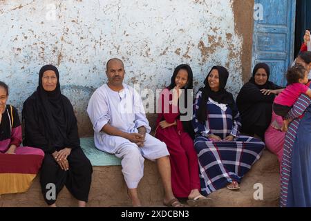 Eine Gruppe von Dorfbewohnern aus Bisaw auf einer Insel im Nil, etwa 90 km nördlich von Assuan, Ägypten, entspannen sich auf einer eingebauten Bank vor ihrem Haus. Stockfoto