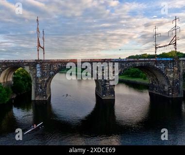 Ruderer fahren durch die Bögen der Pennsylvania Railroad und verbinden die Eisenbahnbrücke über den Schuylkill River in Philadelphia. Stockfoto