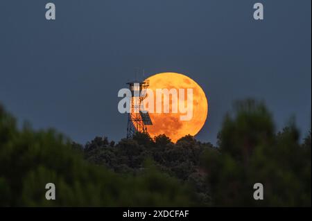 Madrid, Spanien. Juni 2024. Der Vollmond im Juni, bekannt als Erdbeermond, erhebt sich über einem Feueraussichtsturm, der mit der Sommersonnenwende zusammenfällt. Quelle: Marcos del Mazo/Alamy Live News Stockfoto