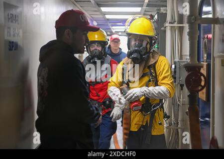 Der Petty Officer der US-Küstenwache 3. Klasse Owen Killian und der Petty Officer 3. Klasse Nolan Cooney warten auf die Erlaubnis, das Chaos des Häuptlings zu betreten, um Alphafeuer zu bekämpfen, während einer Übung an Bord der USCGC Kimball (WMSL 756). Petty Officer 2. Klasse Adrian Colon überwacht die Übung. Die Besatzung führt häufig Übungen sowohl im laufenden als auch im Hafen durch, um sicherzustellen, dass sie bereit ist, auf Notfälle im realen Leben zu reagieren. Kimball bietet Such- und Rettungsdienste, führt lebende Meeresressourcen durch und bekämpft illegale nicht gemeldete und unregulierte Fangeinsätze während seiner Patrouille in der Beringsee. Stockfoto