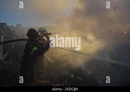 Koropi, Ostattika, Griechenland. Juni 2024. Feuerwehrleute versuchen, ein Feuer im dichten Rauch zu löschen, der während eines Waldbrandes in den östlichen Vororten der griechischen Hauptstadt in einem Fabrikbereich ausgebrochen ist. Die Behörden haben die Bewohner dringend aufgefordert, ein Gebiet am Rand von Athen zu evakuieren, in dem ein großes Waldfeuer durch starke Winde verbreitet wurde. (Kreditbild: © Dimitris Aspiotis/Pacific Press via ZUMA Press Wire) NUR REDAKTIONELLE VERWENDUNG! Nicht für kommerzielle ZWECKE! Stockfoto