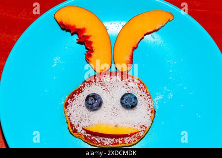 Blauer Teller mit einem süßen Hasengesicht von Pancake. Frühstücksteller für Kinder Stockfoto