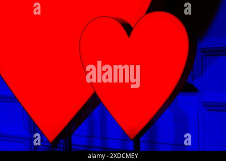 Rote Herzen werden auf blauem Hintergrund beleuchtet. . Die Herzen stehen einander nahe und scheinen zu glühen. Symbol der Liebe und Zuneigung Stockfoto