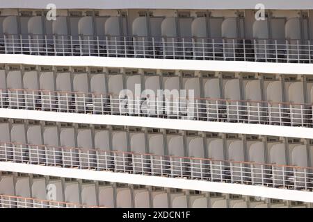 Eine Reihe leerer Kreuzfahrtschiffe befindet sich auf einem Balkon. Die Stühle sind alle in die gleiche Richtung gerichtet und es sind keine Menschen in Sicht. Die Szene Stockfoto