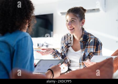 Zwei Frauen sitzen zusammen in gemütlicher Atmosphäre und diskutieren etwas mit Lächeln Stockfoto
