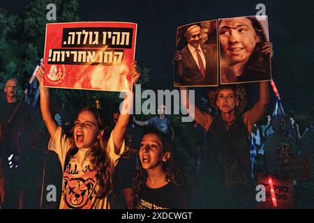 Israel. Juni 2024. Junge Mädchen singen, während sie ein Schild hochhalten, auf dem steht: "Sei Golda Meir, übernimm Verantwortung!" Neben einer Frau, die Fotos der verwundeten israelischen Geisel Naama Levi hält, neben einem Foto des lächelnden Premierministers Benjamin Netanjahu. Tausende von Anti-Netanjahu-Demonstranten demonstrierten in den Dünen neben dem Wohnsitz von Premierminister Benjamin Netanjahu und forderten einen Geiselvertrag und allgemeine Wahlen. Cäsarea, Israel. Juni 2024. (Matan Golan/SIPA USA). Quelle: SIPA USA/Alamy Live News Stockfoto