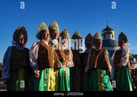 Frauen einer Tanzgruppe in traditionellen russischen Nationalwohnungen stehen vor dem Hintergrund der Orthodoxen Kirche des lebensspendenden Frühlings in St. Petersburg. Am 22. Juni feiert Russland den Tag des Gedenkens und der Trauer - dies ist der Tag des nationalen Gedenkens an die Opfer des Großen Vaterländischen Krieges. Am 22. Juni 1941, um 4 Uhr morgens, begann der Krieg zwischen der Sowjetunion und Deutschland. Am 21. Juni fand eine Gedenkveranstaltung „in der Nacht vom 22. Juni“ statt. Wurde in der Kirche der Heiligen Märtyrer Adrian und Natalia in Staro-Panovo abgehalten. Bei der Veranstaltung fand eine Gedenkfeier für alle Toten statt Stockfoto