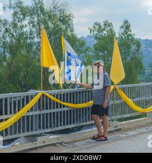 Maagan Michael, Israel - 20. Juni 2024: Menschen mit verschiedenen Zeichen und Fahnen stehen auf einer Brücke, Teil eines Protestaktes gegen die Regierung und A Stockfoto