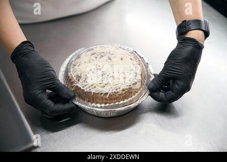 Mitarbeiter der Werkstatt für Halbfertigprodukte packt einen Fleischkuchen Stockfoto