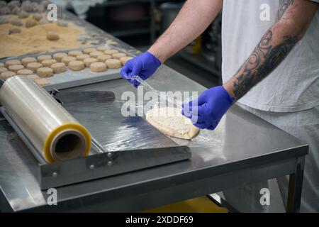 Mitarbeiter der Werkstatt für Halbzeuge packt Khachapuri Stockfoto