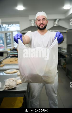 Ein lächelnder Mann hält eine Tüte gefrorener Halbzeuge in den Händen Stockfoto