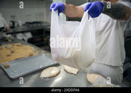Der Mann hält ein Paket mit gefrorenen halbfertigen Khachapuri in den Händen Stockfoto