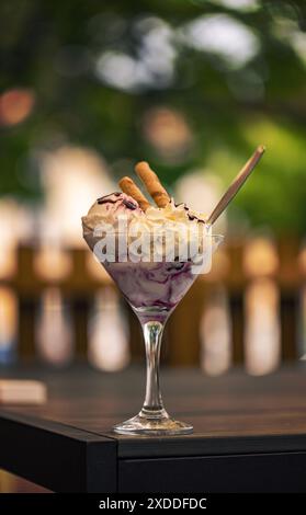 Glasbecher Eis mit Waffeln, Schlagsahne und Beerensauce Stockfoto