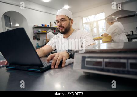 Mann in Brille arbeitet an Laptop in der Werkstatt für Halbzeuge Stockfoto