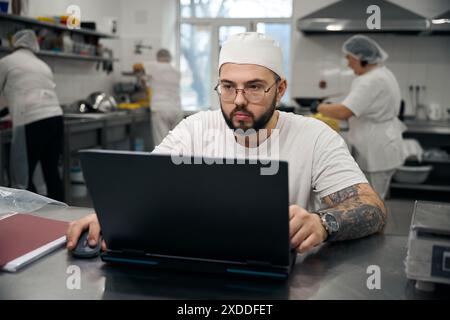 Ein junger Mann in Uniform arbeitet an einem Laptop Stockfoto