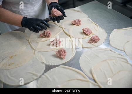 Der Arbeiter macht Hackfleisch auf Pfannkuchen Stockfoto