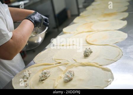 Die Frau legt Fischfüllung auf runde Pfannkuchen Stockfoto