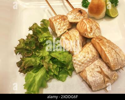 Gegrillter Lachsbauch auf Spießen auf einem weißen Teller. Stockfoto