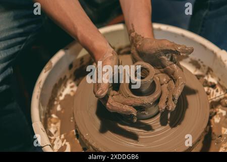 Nahaufnahme von Händen, die Ton auf einem Keramikrad in einer Werkstatt Formen, die die Kunst der Töpferei demonstrieren. Stockfoto