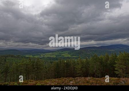 Der Blick vom Craig Lowrigan Hill auf das Balmoral Anwesen mit Blick auf Crathie Church und Balmoral Castle mit großen Sturmwolken darüber. Stockfoto