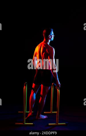 Starker männlicher Athlet zeigt Bewegungen auf parallelen Bars, Studio-Aufnahme Stockfoto