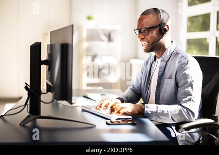 Effiziente Kundenbetreuung: Lächelnder Call-Center-Agent im geschäftigen Büro, der hervorragenden Service über Headset für den Vertriebssupport bietet Stockfoto