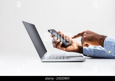 Multitasking-Spezialist für digitales Marketing mit Smartphone und Laptop im Büro, verfolgt den Projektfortschritt für Online-Shops. Stockfoto