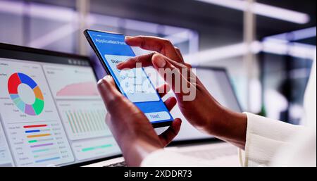 Afroamerikanischer Student füllt Stipendienbewerbung online mit Black Phone und Smart Laptop im College Office aus Stockfoto