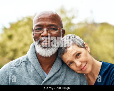 Reifes Paar, Portrait und lieben Outdoor für Bindungen, Urlaub und Ruhestand mit Sonnenschein oder Sonnenschein. Interrassische Ehe, Gesicht und Menschen in der Natur Stockfoto